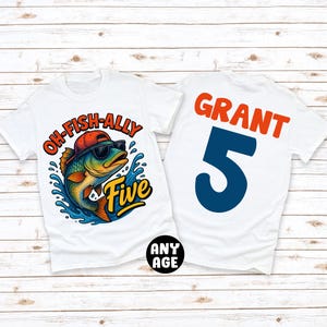 May include: Two white t-shirts. One features a cartoon fish wearing sunglasses and a hat, with the text "OH-FISH-ALLY Five". The other shirt has the name "GRANT" and the number "5" printed on it. The shirts are designed for a fifth birthday.