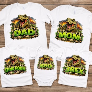 May include: White t-shirts with a dinosaur graphic. The shirts feature a green dinosaur design with the words "DAD", "MOM", "DINO FOUR", "BRO", and "BREX" in green letters. The dinosaur is set against a background of a volcano and palm trees.