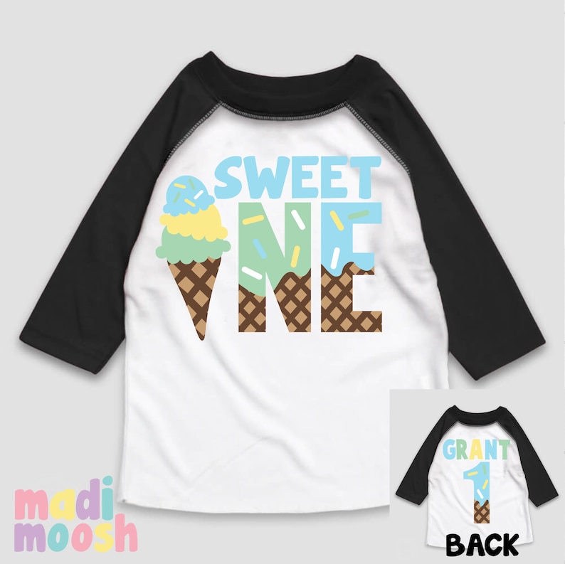 May include: A white and black baseball style shirt with a blue, green, and yellow ice cream cone graphic and the text "SWEET ONE". The back of the shirt has the text "GRANT" and the number "1" in a similar ice cream cone design.
