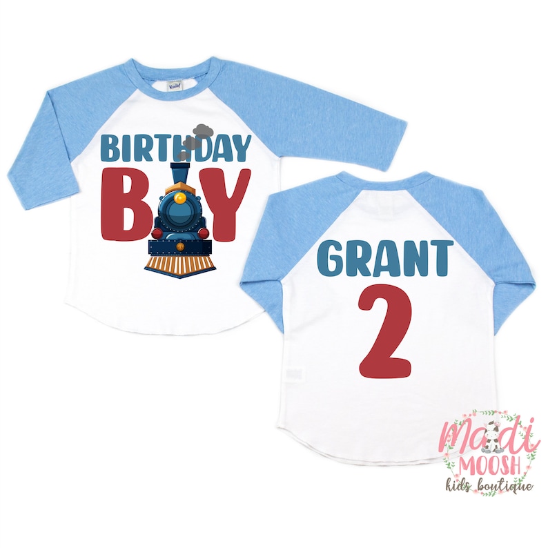 May include: A white and blue baseball style shirt with a train design and the text "Birthday Boy" on the front. The back of the shirt has the name "Grant" and the number "2" in red.