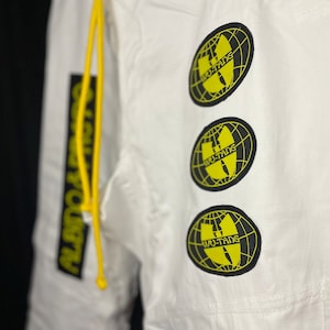 May include: White pants with a yellow drawstring and three black and yellow Wu-Tang Clan logos on the right leg.