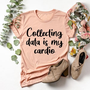 May include: A peach-colored t-shirt with the text "Collecting data is my cardio" printed in black.