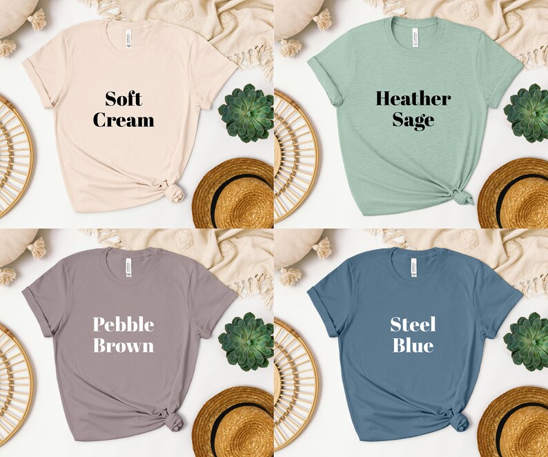 May include: Four t-shirts in different colors with text on the front. The colors are soft cream, heather sage, pebble brown, and steel blue. The text on the shirts reads "Soft Cream", "Heather Sage", "Pebble Brown", and "Steel Blue".