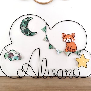 Puede incluir: Decoración de pared con forma de nube de alambre negro con el nombre "Alvaro". Incluye un panda rojo, una luna creciente, una estrella y una pequeña nube, todos decorados con motivos de hojas tropicales. Ideal para una habitación infantil.
