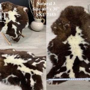 May include: A brown and white sheepskin rug with a natural, mottled pattern. The rug is 40 inches by 30 inches and is labeled "Natural 3" and "SKU 7153".
