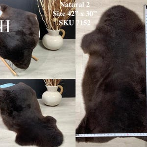 May include: A brown sheepskin rug with a natural, fluffy texture. The rug is laid out flat on a light-colored surface with a measuring tape beside it. The rug measures 42 inches by 30 inches. The text "Natural 2", "Size 42" x 30"", and "SKU 7152" is visible in the image.