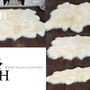 May include: A white sheepskin rug with a soft, fluffy texture. The rug is laid out on a hardwood floor.