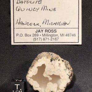 May include: A white datolite geode with a brown exterior. The geode is about 2 inches in diameter and has a hollow center. The label reads "DATOLITE QUINCY MINE HANCOCK, MICHIGAN JAY ROSS P.O. Box 269 Millington, MI 48746 (517) 871-2167".