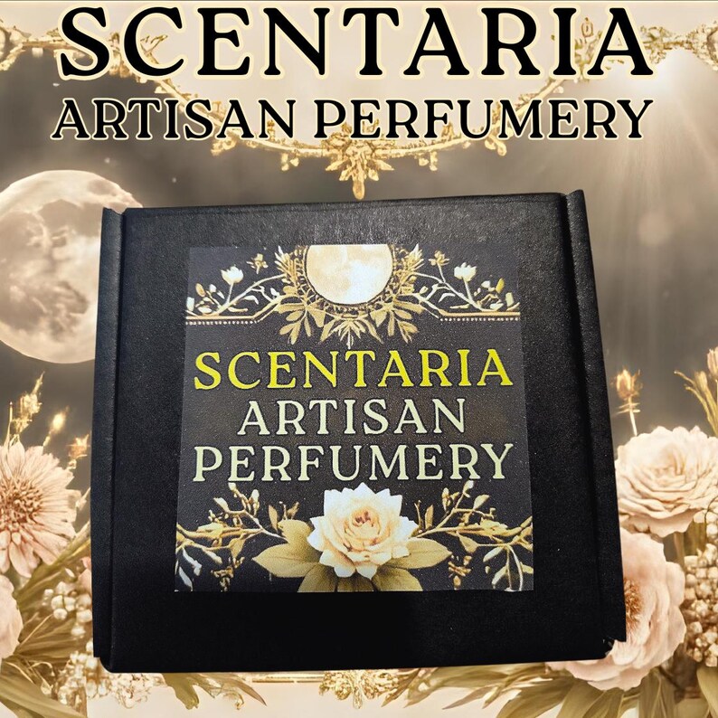 May include: A black box with the text "SCENTARIA ARTISAN PERFUMERY" in gold lettering. The box has a decorative label with a white rose and floral accents. The background features a moon and floral elements.