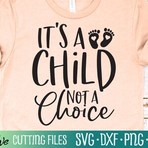 Puede incluir: Una camiseta de color melocotón con texto negro que dice "Es un niño, no una elección" con un par de huellas de pies de bebé sobre el texto.