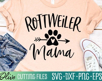 May include: A peach-colored t-shirt with black text that reads "Rottweiler Mama" with a black paw print with a white heart in the center and a black arrow pointing to the right.