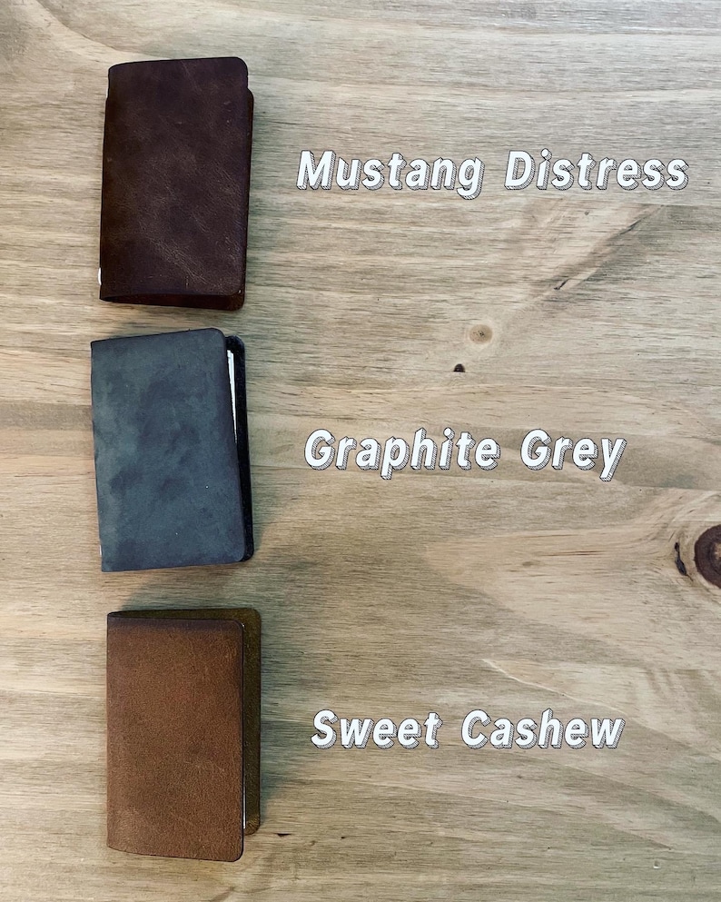 May include: Three leather notebooks in different colours: brown, grey, and brown. The notebooks are labelled "Mustang Distress", "Graphite Grey", and "Sweet Cashew".