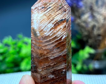 May include: A clear quartz crystal point with brown and white inclusions. The crystal is faceted and has a pointed tip.