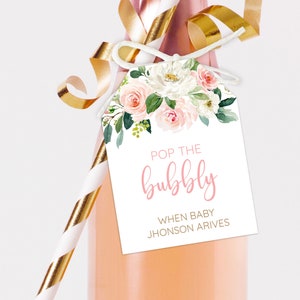 May include: A white gift tag with pink floral illustrations and the text "Pop the bubbly when baby Jhonson arrives".