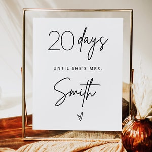 May include: A white sign in a gold frame with the text "20 days until she's Mrs. Smith" in black script.