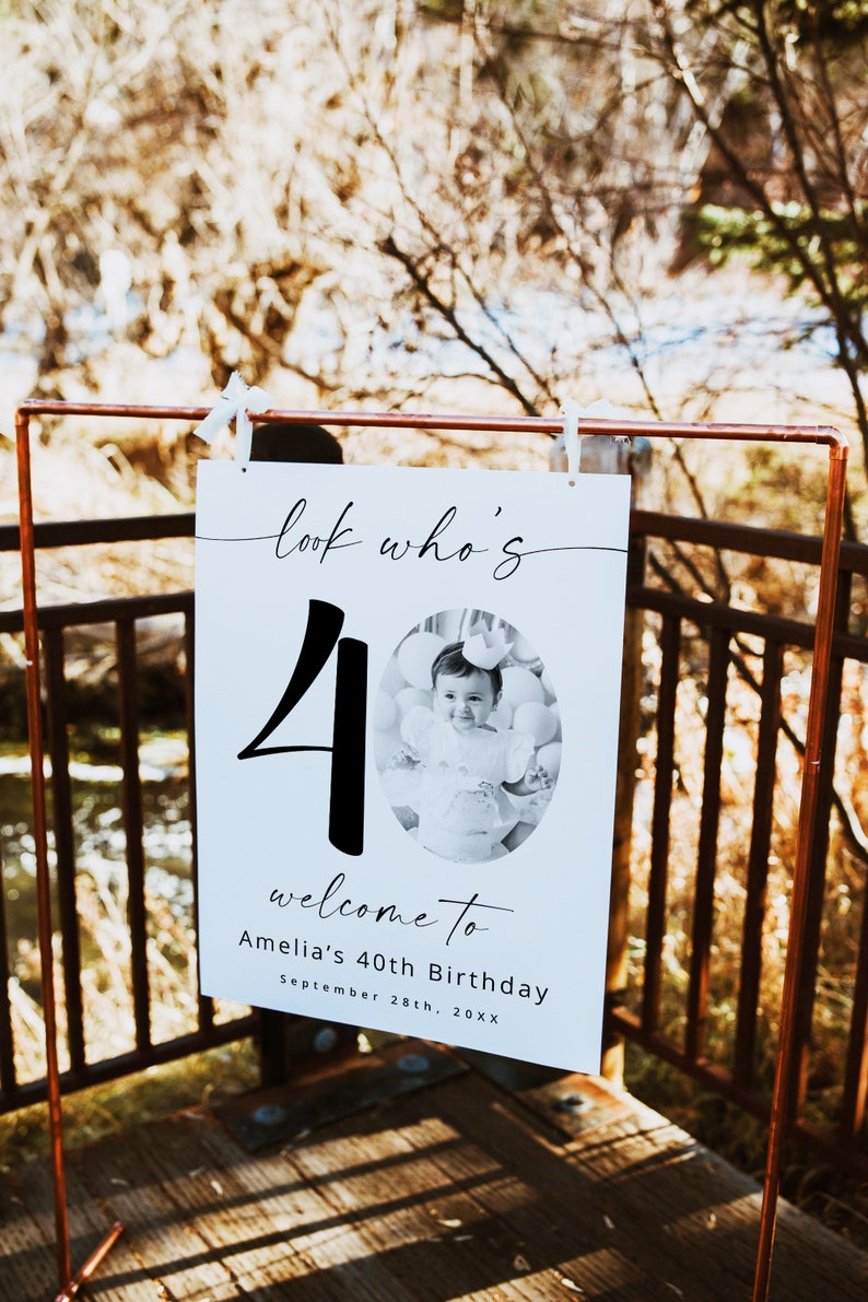 K&ouml;nnte beinhalten: Ein wei&szlig;es Schild mit schwarzem Text, der "look who's 40" lautet, mit einem Foto eines Kindes, das eine Krone und ein schwarz-wei&szlig;es Kleid tr&auml;gt. Der Text unter der Zahl lautet "welcome to Amelia's 40th Birthday September 28th, 20XX".
