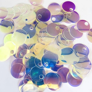 Könnte beinhalten: Eine Ansammlung von schillernden, runden Pailletten in verschiedenen Größen. Die Pailletten haben ein Loch in der Mitte und reflektieren Farben wie Lila, Blau und Gelb. Diese dekorativen Pailletten sind ideal für Bastelarbeiten und Verzierungen.