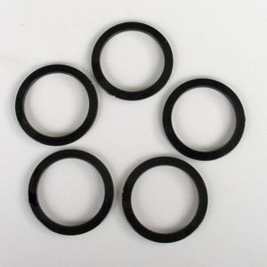 May include: Five black rubber O-rings arranged on a white surface. Each ring is circular with a consistent thickness. The rings are evenly spaced, with a slight variation in their positioning. The image is well-lit, highlighting the texture and shape of the rings.