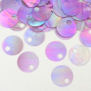 May include: A collection of circular, iridescent sequins featuring a single off-center hole. These flat, thin discs display a shimmering, pearlescent finish with shifting hues of light purple, pink, and blue, scattered across the frame.