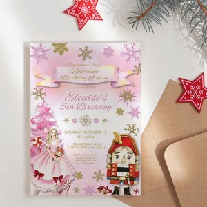 Op de afbeelding: Een roze en gouden Nutcracker Birthday Party uitnodiging met een illustratie van een ballerina en een notenkraker. De uitnodiging bevat de tekst "Elouise's 5th Birthday" en evenementdetails. Een bruine envelop en rode sterdecoraties zijn ook zichtbaar.
