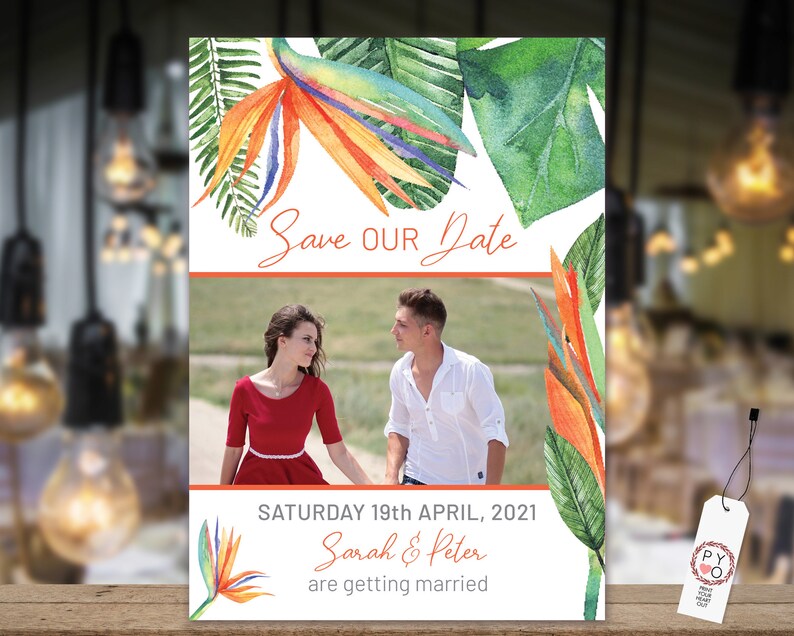 May include: Save the date card with a tropical theme. The card features a photo of a couple in front of a beach with a watercolor illustration of tropical leaves and flowers. The text on the card reads "Save Our Date" and "Saturday 19th April, 2021 Sarah & Peter are getting married."