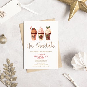 May include: A Christmas-themed invitation with the words "Hot Chocolate" in a script font. The invitation features illustrations of three hot chocolate cups with whipped cream and festive toppings. Decorative elements include a gold star, ornaments, and a snowflake.