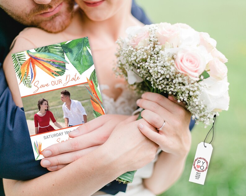 May include: A tropical-themed save the date card with a photo of a couple in the background. The card features a colorful bird of paradise flower and green leaves. The text "Save Our Date" is written in orange script. The date "Saturday 18th" is written below the photo.