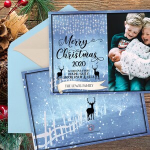 May include: Christmas card with a blue and white winter scene, featuring the text "Merry Christmas 2020" and a family photo. The card includes a light blue envelope and decorative elements like pinecones and berries.