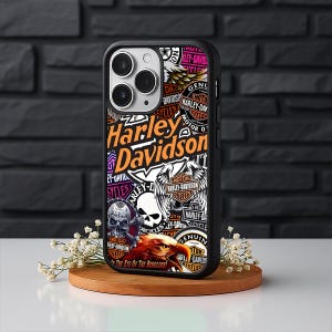 May include: Black phone case featuring a collage of Harley-Davidson logos, skulls, and eagle graphics. The design includes the Harley-Davidson name in orange and white, with additional text in various fonts and colors. The case is on a wooden stand.