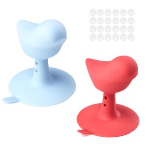 May include: Two silicone bottle stoppers in the shape of birds. One is light blue, the other is red. Each has a round base and a bird-shaped top. A set of small, clear, round discs is in the background.