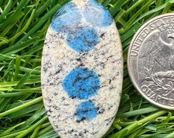 May include: Oval shaped cabochon of blue kyanite in a white and gray matrix. The stone is about the size of a US quarter.