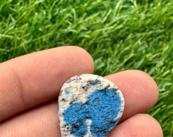 May include: A teardrop-shaped cabochon of blue and white kyanite, a gemstone known for its calming energy. The stone is set in a silver bezel and has a polished finish.