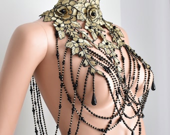 May include: A gold and black beaded and embroidered choker necklace with a floral design. The necklace has multiple strands of black beads and features a large floral design with gold embroidery and black beads.