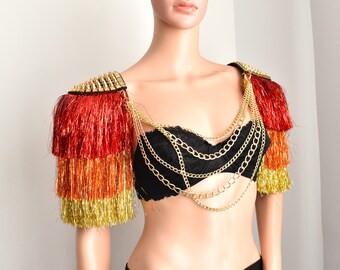 May include: A gold chain necklace with multiple strands and a red, orange, and gold fringe shoulder piece with gold spikes.