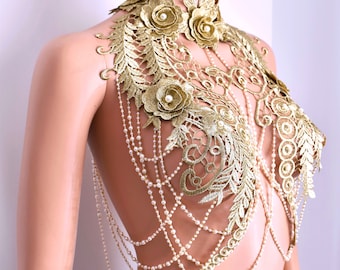 May include: A gold lace and pearl chain body jewelry piece. The lace is in a floral pattern with small pearl accents. The chain is made of small white pearls.