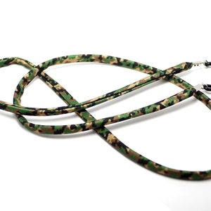 May include: A camouflage-patterned eyeglass strap with black metal clasps. The strap is made of a soft, flexible material and is designed to keep glasses secure.