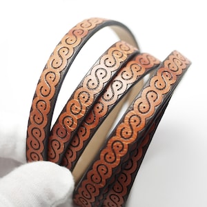 May include: Four strands of brown leather cord with an intricate orange design. The cord is woven together in a decorative pattern.