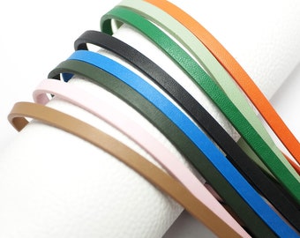 May include: Assortment of leather cord in various colors, including brown, pink, green, blue, black, and orange. The cords are arranged in a circular pattern, with the ends of each cord overlapping.