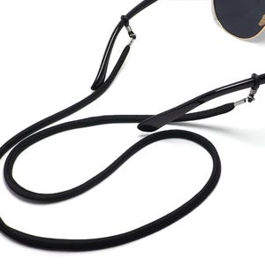Puede incluir: Correa de gafas de sol negra con un cordón negro que se puede llevar alrededor del cuello. La correa está unida a las gafas de sol con bucles metálicos.