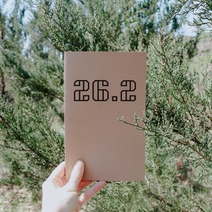 May include: A brown notebook with the number "26.2" printed in black on the front cover.