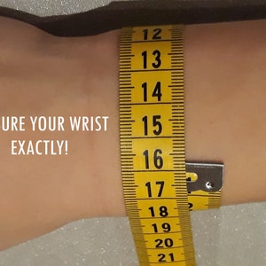 May include: A yellow measuring tape is wrapped around a wrist to measure its circumference. The tape shows measurements from 12 to 21 inches. Text on the image reads: MEASURE YOUR WRIST EXACTLY!