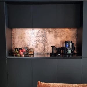 Copper splashback recessed in a coffee bar with matte black cabinets