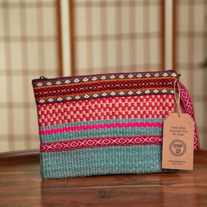 May include: A teal, pink, red, and white woven clutch with a brown tag that reads "Handcrafted Textiles from The Andes".