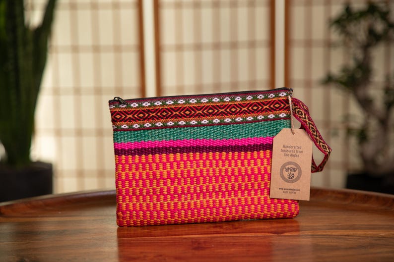 May include: A colorful woven clutch bag with a zipper closure and a brown tag that reads "Handcrafted Treasures from The Andes".