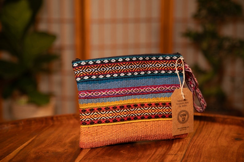 May include: A colorful woven clutch bag with a brown leather strap and a tag that reads "Handmade Treasures from the Andes".