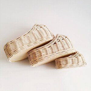 May include: Two woven wicker baskets, one stacked on top of the other. The baskets are cream colored and have a natural woven pattern.