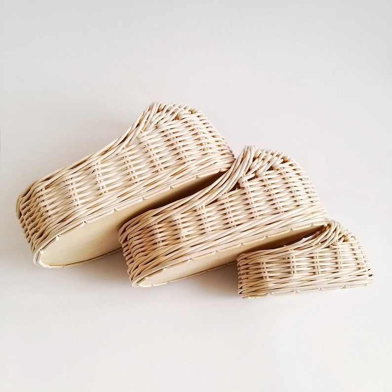 May include: Two woven wicker baskets, one stacked on top of the other. The baskets are cream colored and have a natural woven pattern.