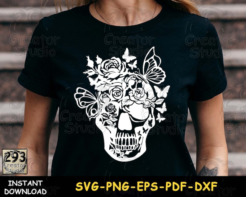 May include: A black t-shirt with a white design of a skull with flowers and butterflies. The design is intricate and detailed, with the skull's eyes replaced by flowers and butterflies.