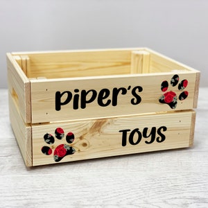 Puede incluir: Una caja de juguetes de madera con las palabras "Piper's Toys" y un diseño de huella de pata floral.