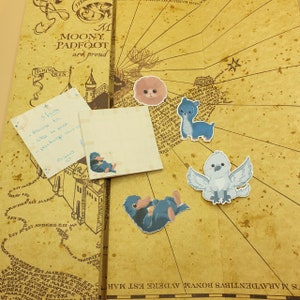 Peut inclure: Une carte vintage aux couleurs brun, crème et jaune. La carte comporte du texte en anglais et des illustrations d'un oiseau bleu, d'un hibou blanc, d'une créature bleue et d'une créature rose. La carte comprend également quelques notes manuscrites sur de petits morceaux de papier.